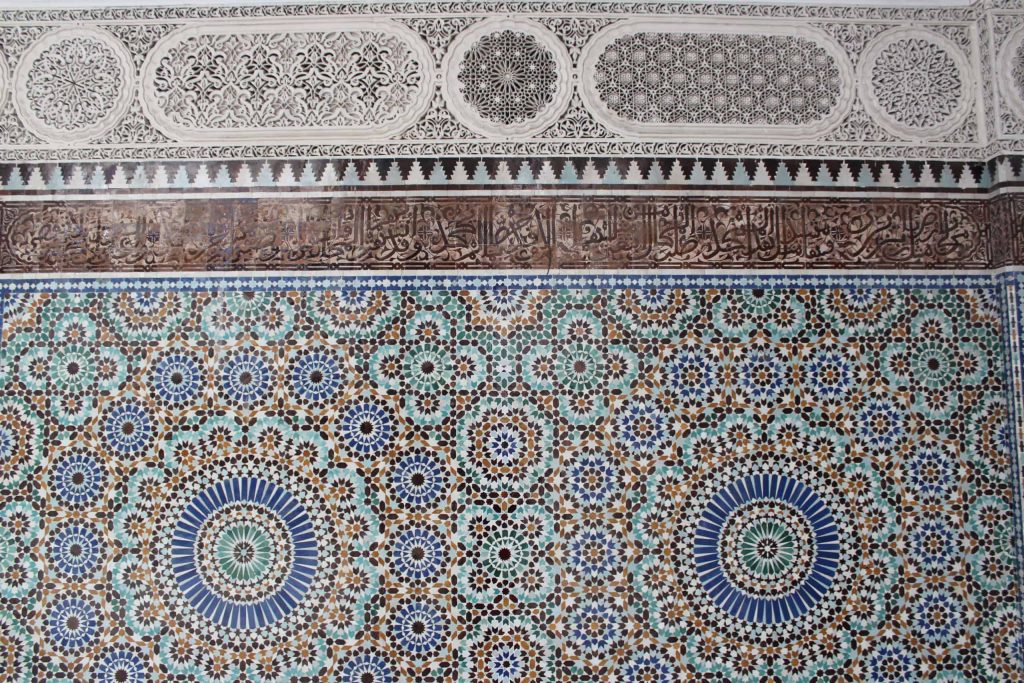 A close up photo of the detailed tile mosaics and carved stucco patterns of the walls of the mosque.